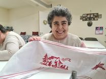 Erika happily shows her embroidered handiwork to the camera.