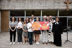 Class photo with Bischöfliches Gymnasium Paulinum holding up a poster showing the donation total.